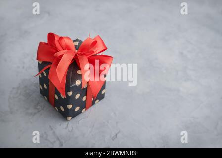 Polka dot Gift box with red ribbon on grey background closeup Stock Photo