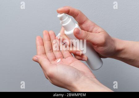 Female hands applying antibacterial liquid soap close up. On gray background. Stock Photo