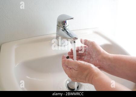 Washing hands under the faucet with water and soap, hygiene concept against the risk of infection with a virus, copy space, selected focus, narrow dep Stock Photo