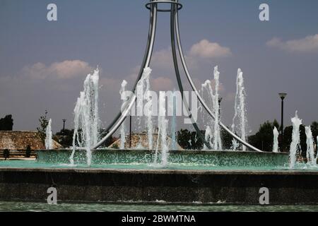 a large round shaped fountain works by splashing a large jet of water up Stock Photo