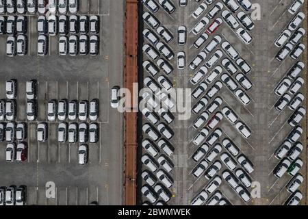 New car lined up aerial view. Port of import and export business logistic to dealership for sale. Automobile and automotive car parking lot for commer Stock Photo