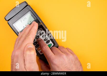 person typing in PIN at POS payment terminal while covering keypad with free hand to prevent spying out of personal data Stock Photo