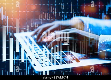Hands on a computer keyboard with various charts showing stock prices Stock Photo