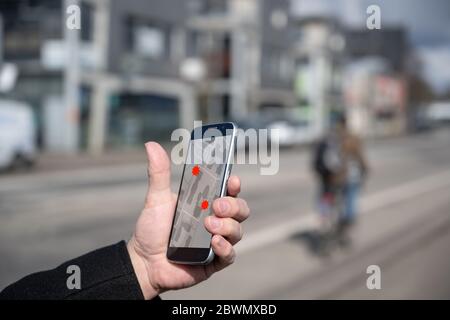 Hand with mobile phone, tracking  people which could spread the coronavirus,  the app can protect against infection, but is controversial when it come Stock Photo