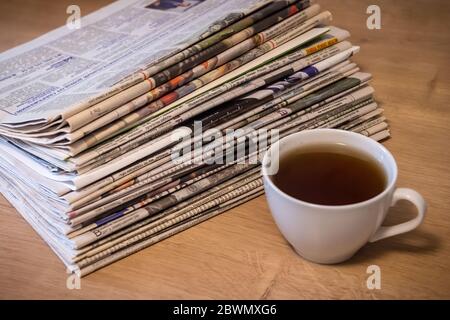selective focus of the cup of tea stacking newspapers folded place on wooden table Stock Photo