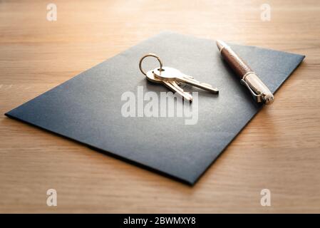 Keys, pen and envelope on the wooden table. Selling or rental of flat, house or another real estate or object. Symbol of agreement. Stock Photo