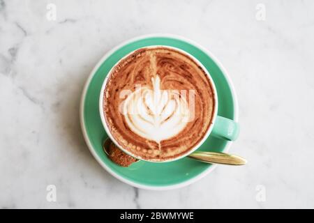 A cup of coffee with latte art on top on light background, closeup top view Stock Photo