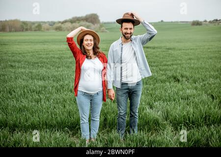 Portrait of a lovely couple standing together on the greenfield. Happy couple expecting a baby, young family concept Stock Photo