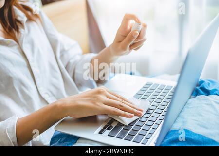 People alcohol spray laptop keyboard cleaning for personal hygiene and cleanliness virus protection. Stock Photo