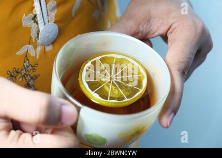 Close up of women hand drinking lemon tea  Stock Photo
