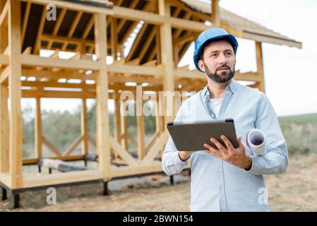 Architect or builder using digital touchpad on the construction site outdoors. Concept of building and designing wooden frame house Stock Photo