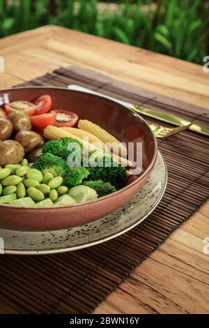Vegan Buddha Bowl with edamame beans, cherry tomato, cucumber, baby potatoes, corn, tofu on table Stock Photo