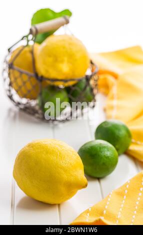 Organic lemons and limes in a basket on white background Stock Photo