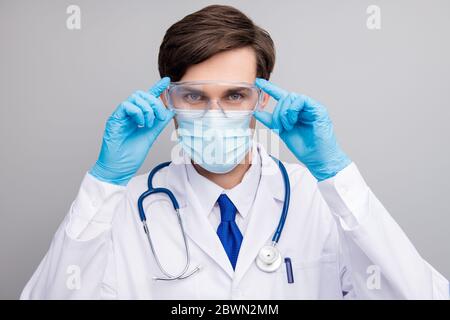 Closeup photo of attractive handsome serious doc guy professional surgeon specialist wear blue gloves facial protective mask medical uniform lab coat Stock Photo
