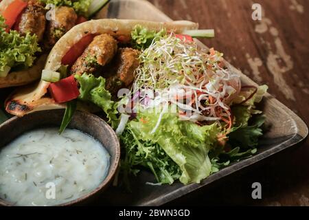 Falafel Pocket Pita. Spread with babaganoush,with coleslaw & falafel served with side salad & vegan tzatziki. Stock Photo