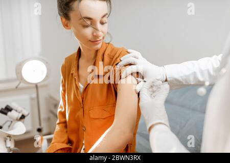 Healthcare worker gives an injection of a vaccine or some medication to a young girl in the office. Vaccination concept Stock Photo