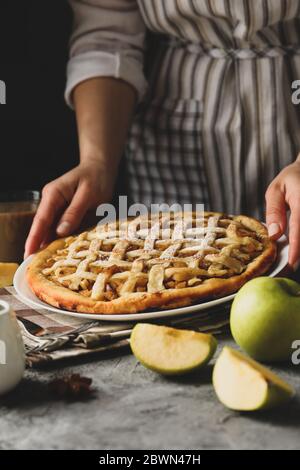 Housewife hold tasty apple pie on gray table. Homemade food Stock Photo