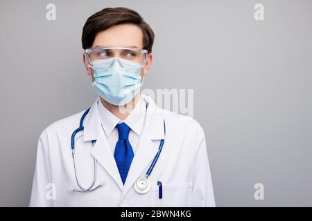 Closeup photo of attractive serious virologist doc guy professional surgeon listen patient wear facial protective mask medical uniform lab coat Stock Photo