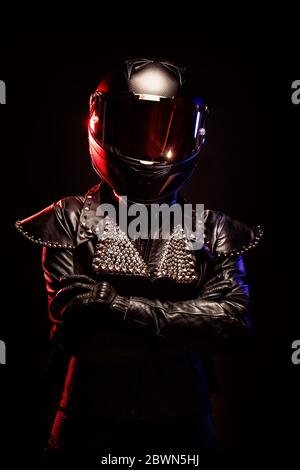 Portrait of a young female biker wearing a studded leather jacket and a black helmet Stock Photo