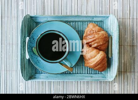 Cup of coffee with croissant  on blue bamboo tray outdoor, top view Stock Photo