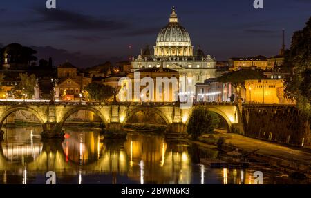 Rome at Night - A panoramic night view of Tiber river at Sant' Angelo Bridge, with St. Peter's Basilica towering in background, Rome, Italy.