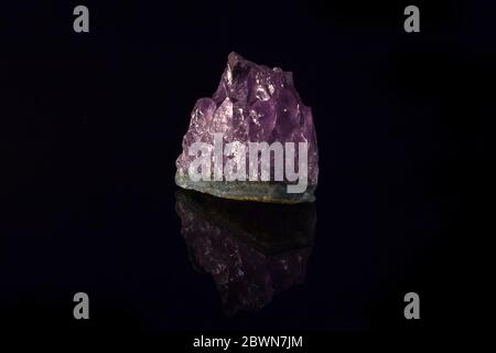 Purple amethyst semiprecious stone, isolated on black background, with reflection Stock Photo