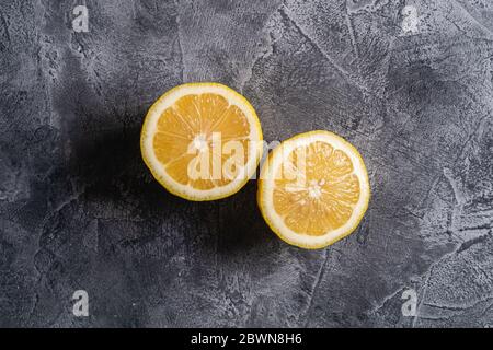 Two lemon slices, tropical citrus fruits on grey concrete background, top view Stock Photo
