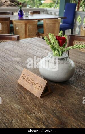Wooden reserved sign on a  table in tropical restaurant Stock Photo