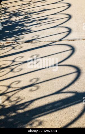 Iron fence casts shadows on sidewalk; Heart of the Rockies Regional Medical Center Healing Garden; Salida; Colorado; USA Stock Photo