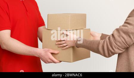 Transfer from hand to hand. Courier delivers boxes and gives to customer, panorama, cropped, studio shot Stock Photo