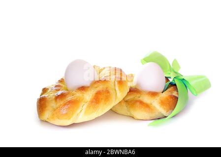 Two traditional Easter breads made of sweet yeast dough in the shape of a nest with boiled eggs and a green ribbon, isolated on a white background, se Stock Photo