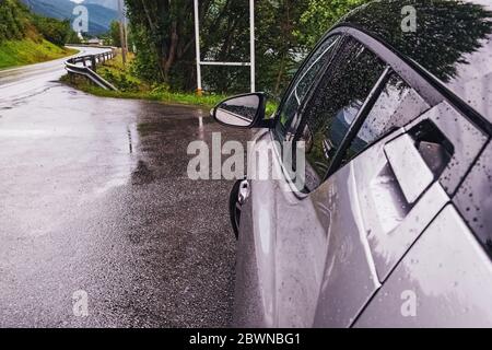 Car standing on the roadside on small country road on rainy day. Automobile travelling, road trip Stock Photo