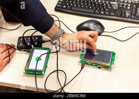 Man tapping, interacting with an lcd touch screen display on a single board microcontroller Progamming open source hardware micro controller apps tech Stock Photo