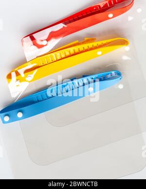 Set of three colorful protective face shields, closeup, closed composition. Group of anti viral plastic portable efficient face protection Stock Photo