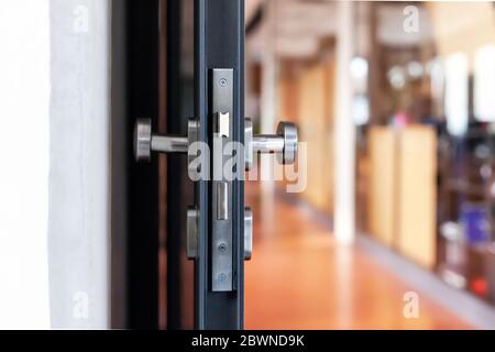 Open unlocked doors in an empty secure vacant corporate business area, nobody, door knob lock side closeup. Door left open, office building security Stock Photo