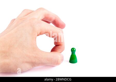 Hand flicking away a small game piece, pawn, finger flick gesture closeup. Layoffs and unemployment abstract business concept Employee cutback Stock Photo