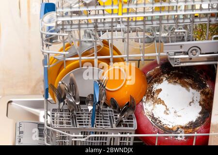 Many different dishes inside an open loaded dishwasher side view. Washing cutlery and various dishware simple concept, natural, domestic Stock Photo