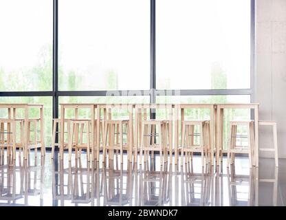 Many empty wooden stools near a table in a corporate lobby area, luch room, calm business canteen, no people, nobody. Vacant seats, company lunchroom Stock Photo