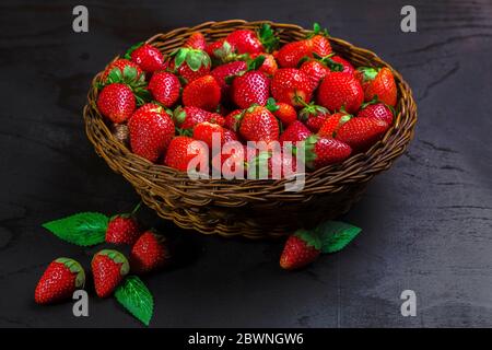 Rattan bowl with fresh strawberries on black table Stock Photo