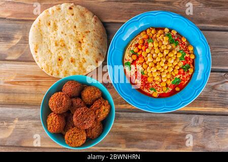 Falafel balls, pita bread ,hummus, chickpea and spices on wooden rustic table. Falafel plays an iconic role in Israeli cuisine and is widely considered to be the national dish of the country. Stock Photo