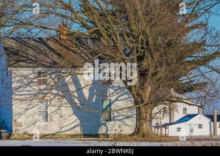 Tree shadows crossing a classic farmhouse in winter in central Michigan, USA [No property release; available for editorial licensing only] Stock Photo