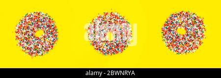 Multicolored sugar pastry topping in form of donuts on yellow background. Funny food. Top view Stock Photo