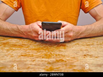 Mid section of man holding smartphone in both hands Stock Photo