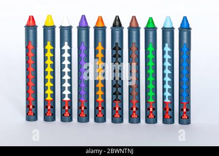 Ten different colored crayons standing on a white surface Stock Photo