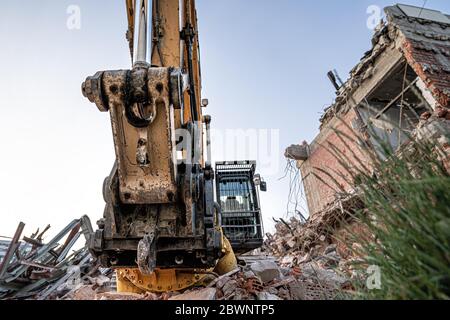 Excavator destroing ruins and olfd building. Wide angle closeup shot. Stock Photo