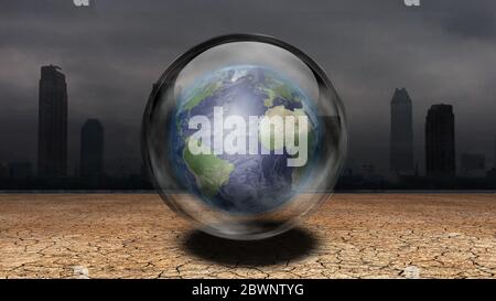 Symbolism. Earth in the bubble hovers above arid land. City at the horizon Stock Photo