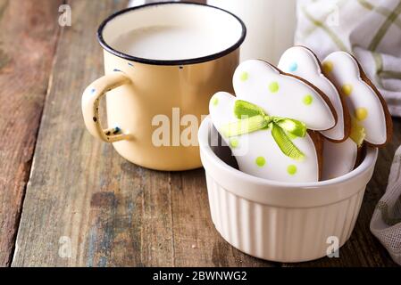 Rabbit shaped Easter cookies, hand-made with cup of milk. Decorated with fondant icing on old wooden background Stock Photo