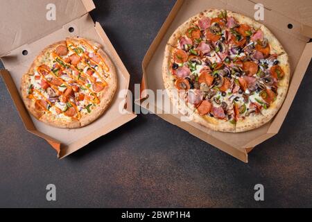 Two Italian pizzas with tomato,pepperoni, onion, green bell pepper, Mozzarella cheese, sauce. Delivery food. View from above. Stock Photo