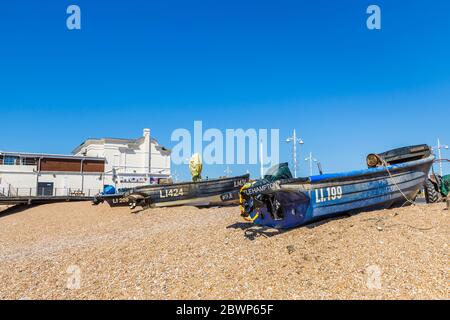 Small fishing boats beached on the shingle beach and lobster pots by the pier at Bognor Regis, a seaside town in West Sussex, south coast England Stock Photo