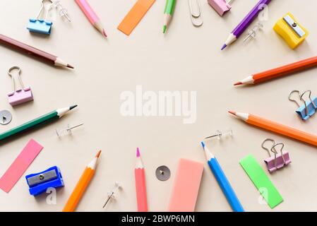 Top view blank office desk table with empty space on pastel beige backgroud. Flat lay. Paper clips, sharpener, pencils, stickers and other school supp Stock Photo